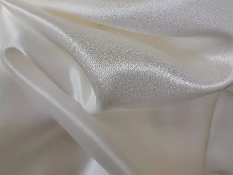 Makroaufnahme eines luxuriösen 22 mm dicken Maulbeerseidenstoffs mit elegantem Faltenwurf und natürlichem Glanz, der für hochwertige Nachtwäschekollektionen von Eigenmarken verwendet wird.