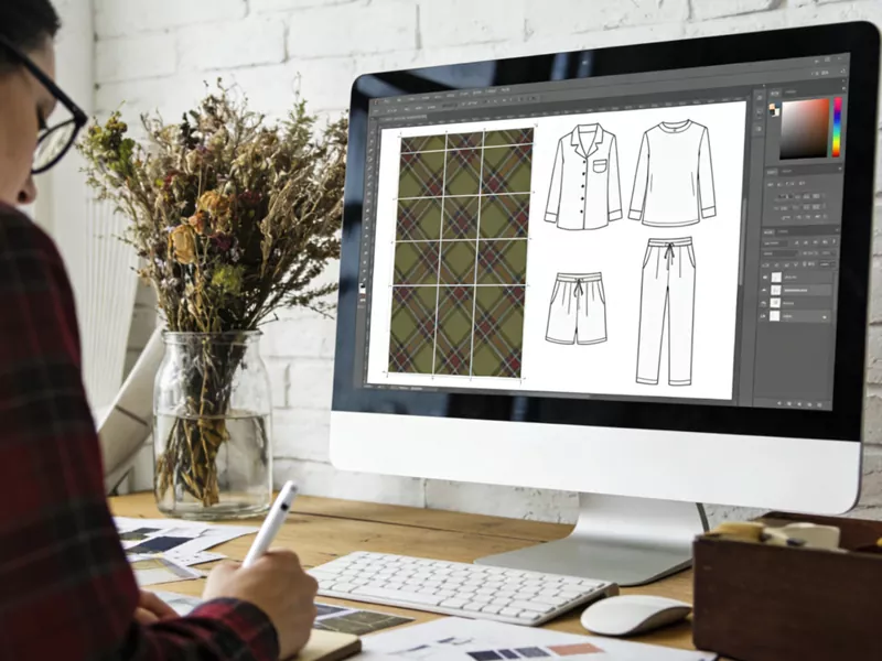 Concepteur professionnel de vêtements de nuit réalisant sur ordinateur des croquis techniques à plat et un modèle de tissu écossais pour un pack technique de pyjama personnalisé.