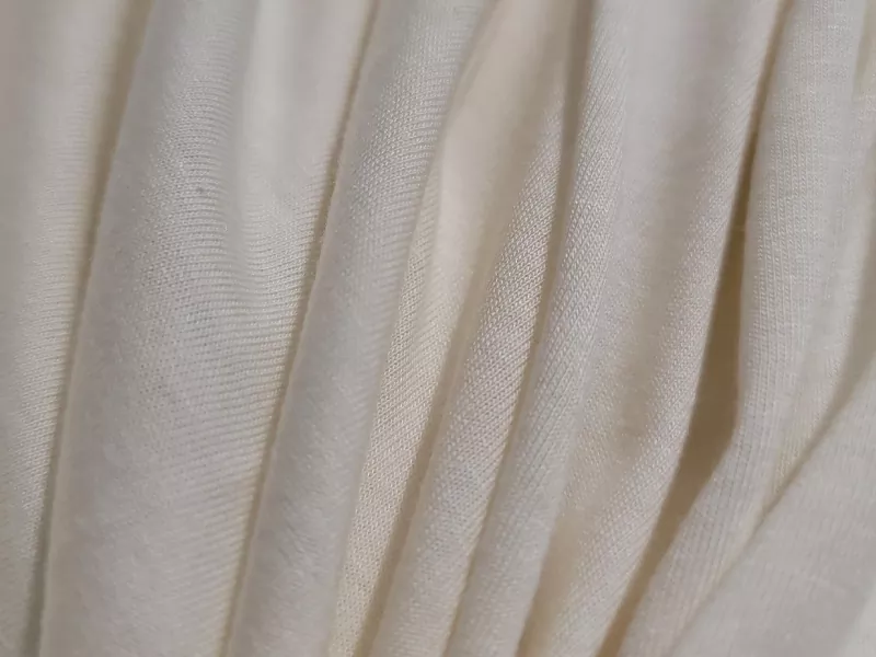 Makroaufnahme eines hochwertigen Bambusviskosestoffs mit eleganter vertikaler Drapierung, der eine ultraweiche Textur und ein atmungsaktives Gestrick für Nachtwäsche der Eigenmarke zeigt.