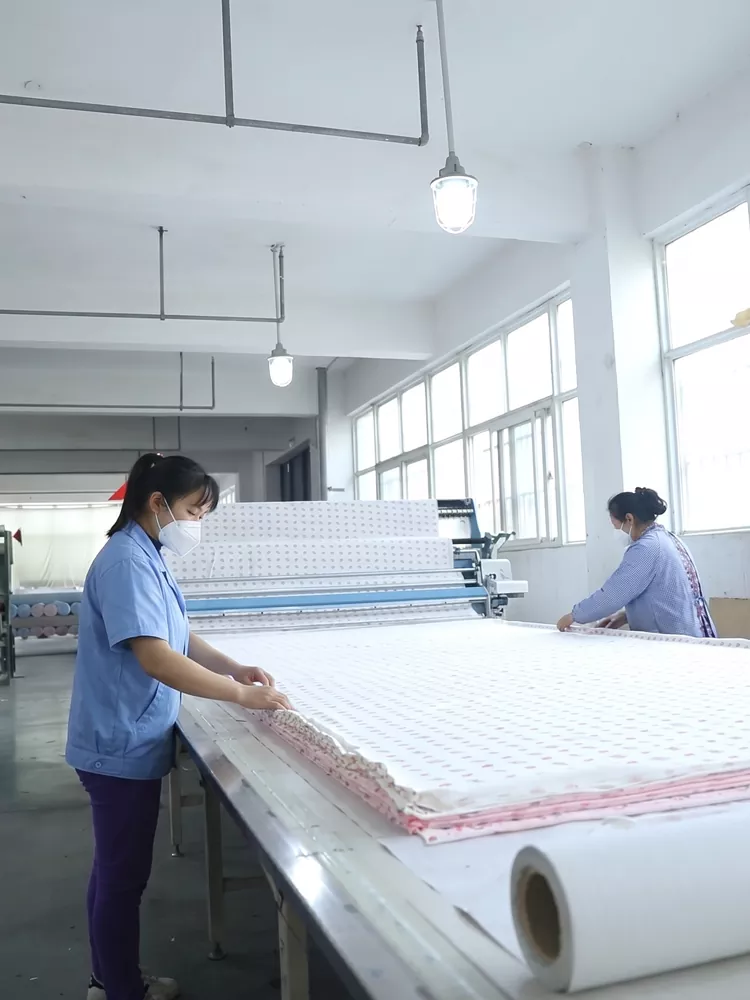 Workers laying and cutting fabric with minimal waste for custom baby onesie manufacturing