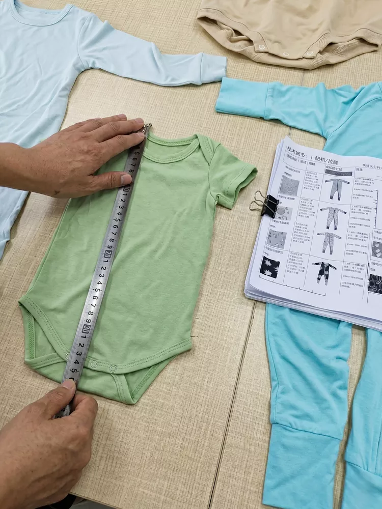 Quality control inspector measuring a baby onesie against tech pack sizing specifications