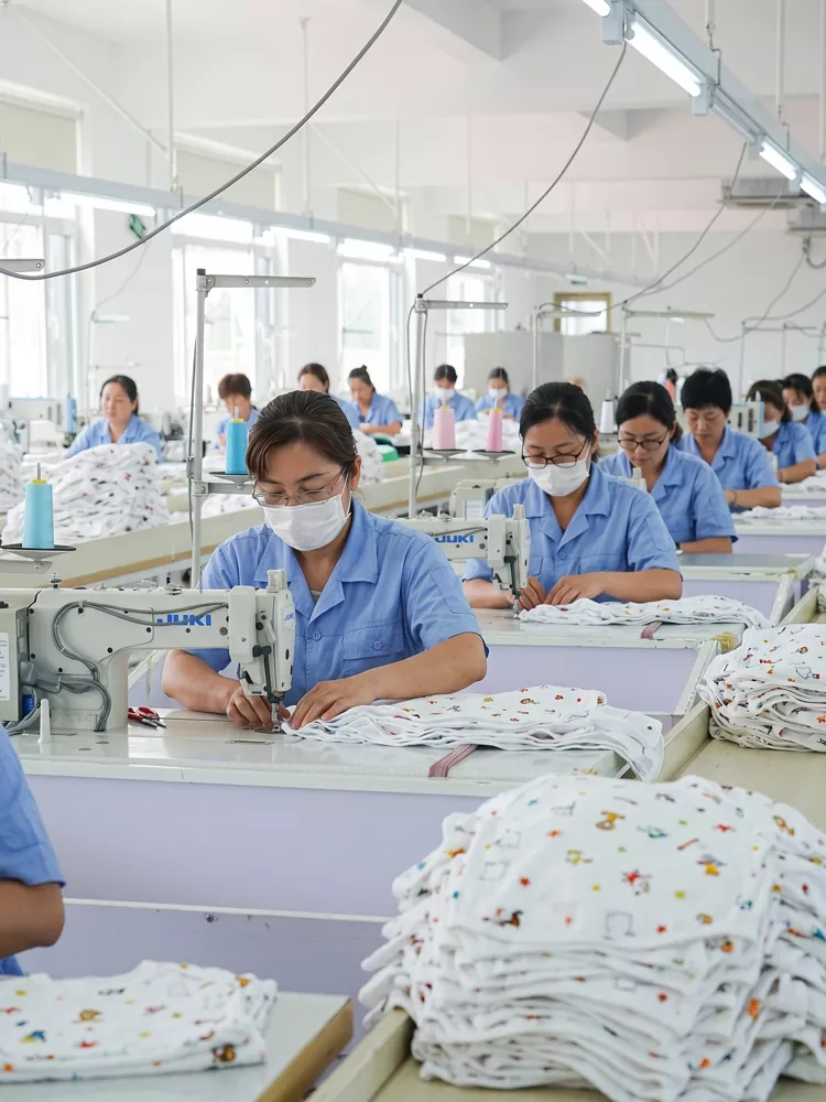 Skilled operators sewing baby clothes in a dedicated babywear OEM factory line