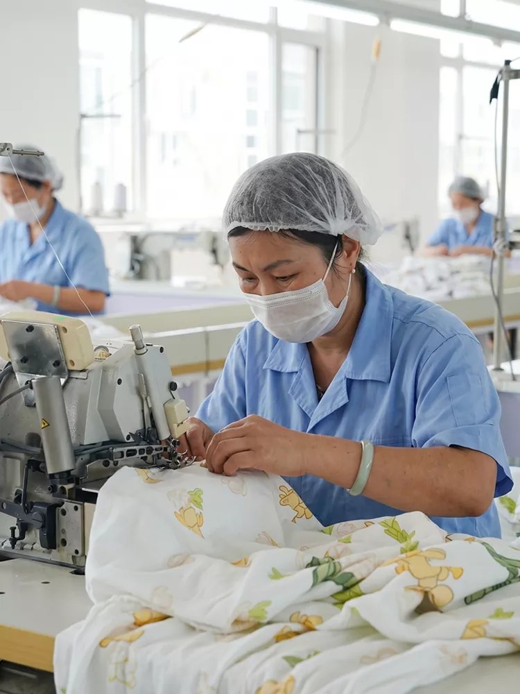Skilled operator sewing custom printed baby sleepwear in our professional baby onesie manufacturing factory