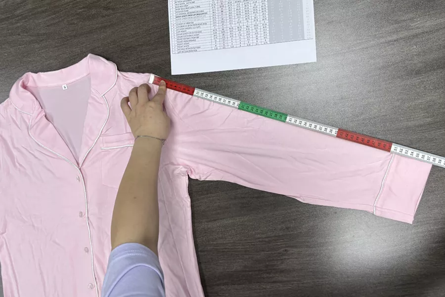 Factory QC inspecting custom loungewear sleeve measurement against tech pack at BSCI-certified PJGarment factory