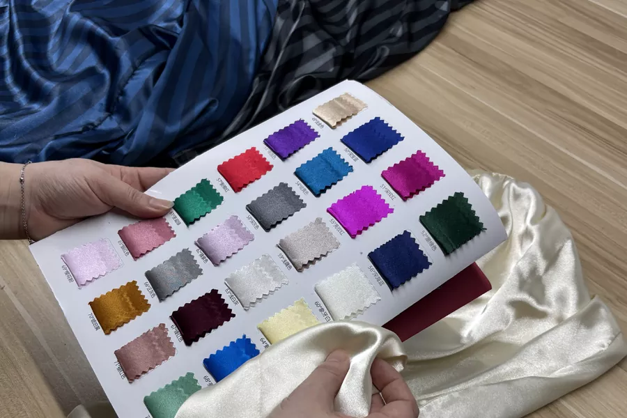 Factory QC inspecting custom silk pajamas against color swatches at PJGarment factory